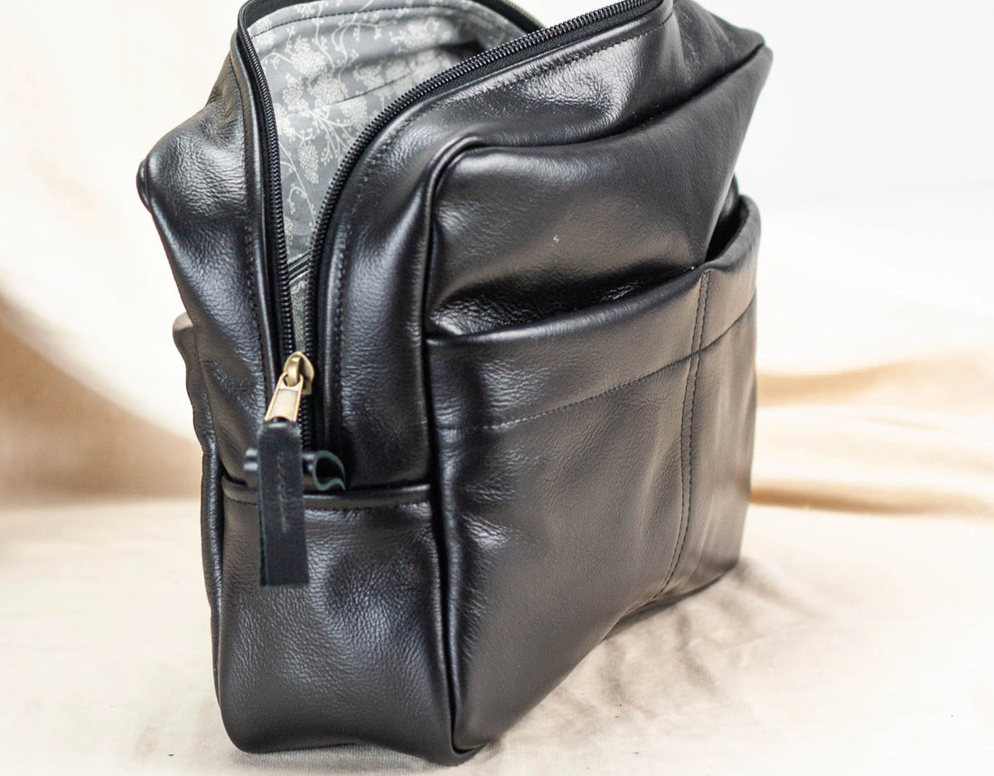 Black leather bag organizer with a gold zipper on a light background