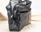 Black leather bag organizer with a gold zipper on a light background