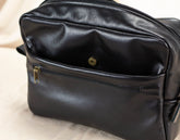 Black leather bag insert with a gold zipper on a light background