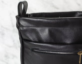 Close-up of a black leather bag organizer with a zipper on a light gray background