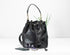 Black leather bucket bag with sunglasses and phone on a white background