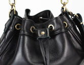 Black leather handbag with gold hardware on a white background