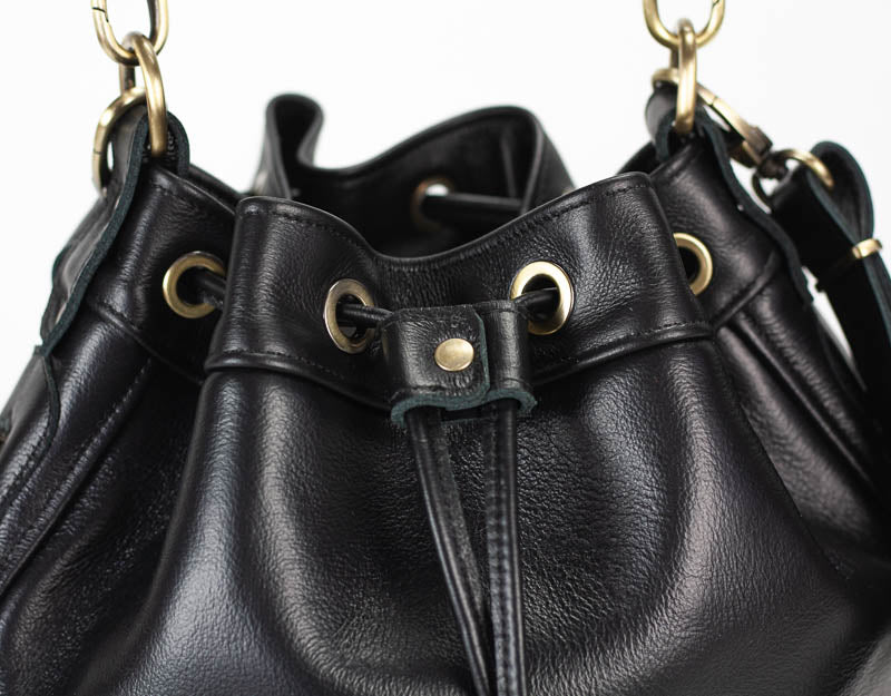 Black leather handbag with gold hardware on a white background