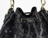 Black woven handbag with gold hardware on a white background