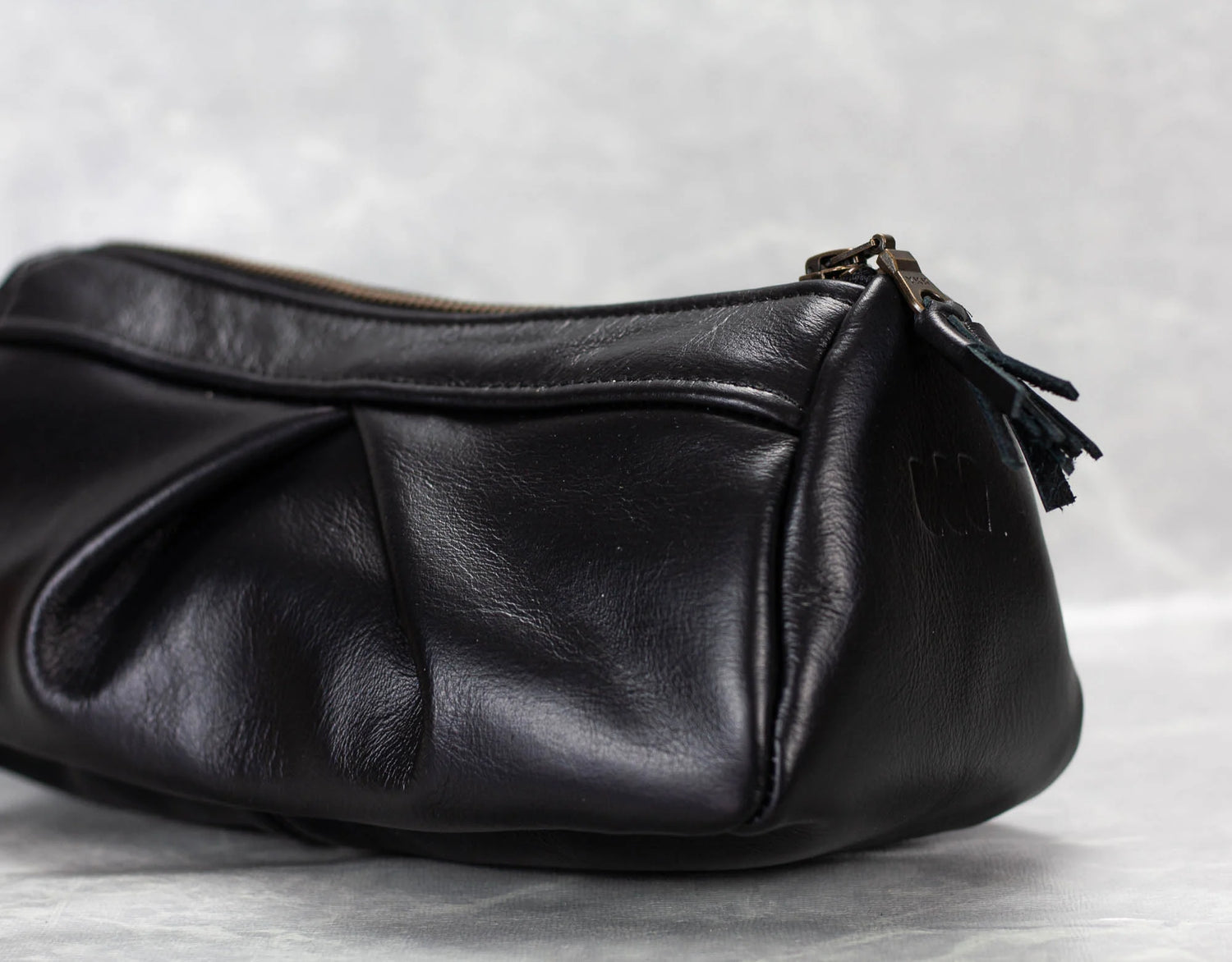 Black leather handbag with a zipper on a light gray background
