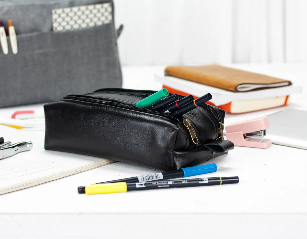 Black pencil case with pens on a desk#color_black