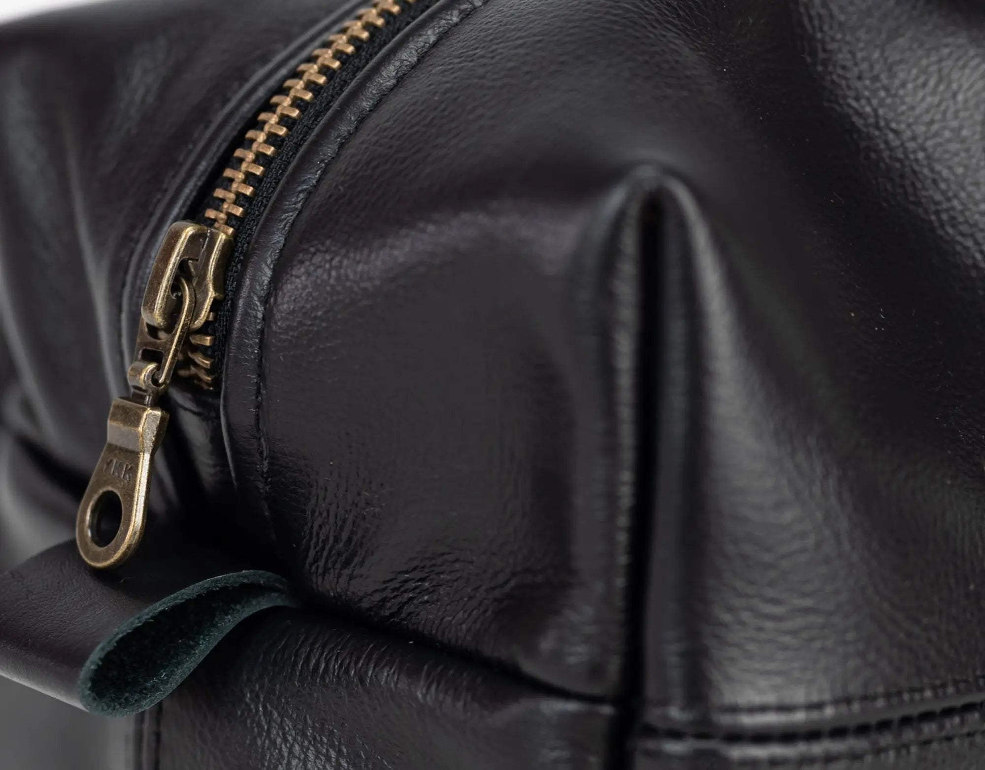 Close-up of a black leather bag with a gold zipper.