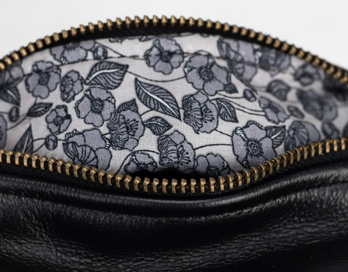 Close-up of a black leather pouch with a floral patterned interior.#color_black