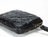 Black woven leather pouch with a strap on a light gray background