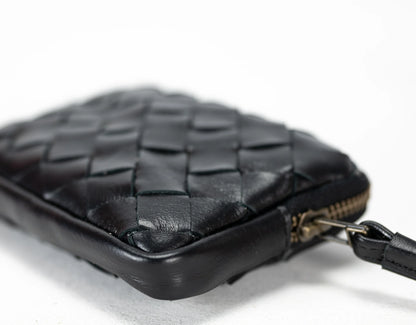 Black woven leather pouch with a strap on a light gray background