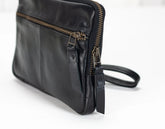 Black leather bag with gold zipper on a white background