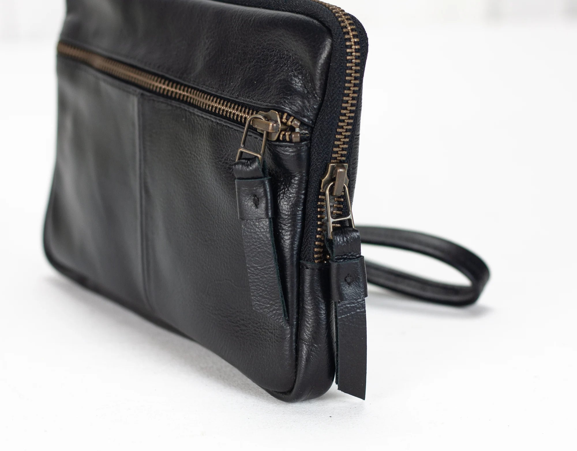 Black leather bag with gold zipper on a white background