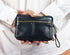 Person holding a black leather wallet with a strap on a white background