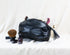 Black leather pouch with makeup items on a white background