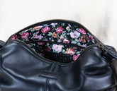 Black leather bag with floral patterned zipper on a white background