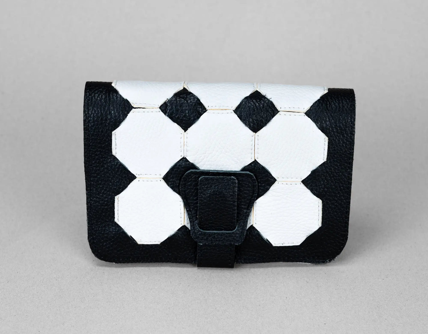 Black and white geometric patterned clutch bag on a gray background