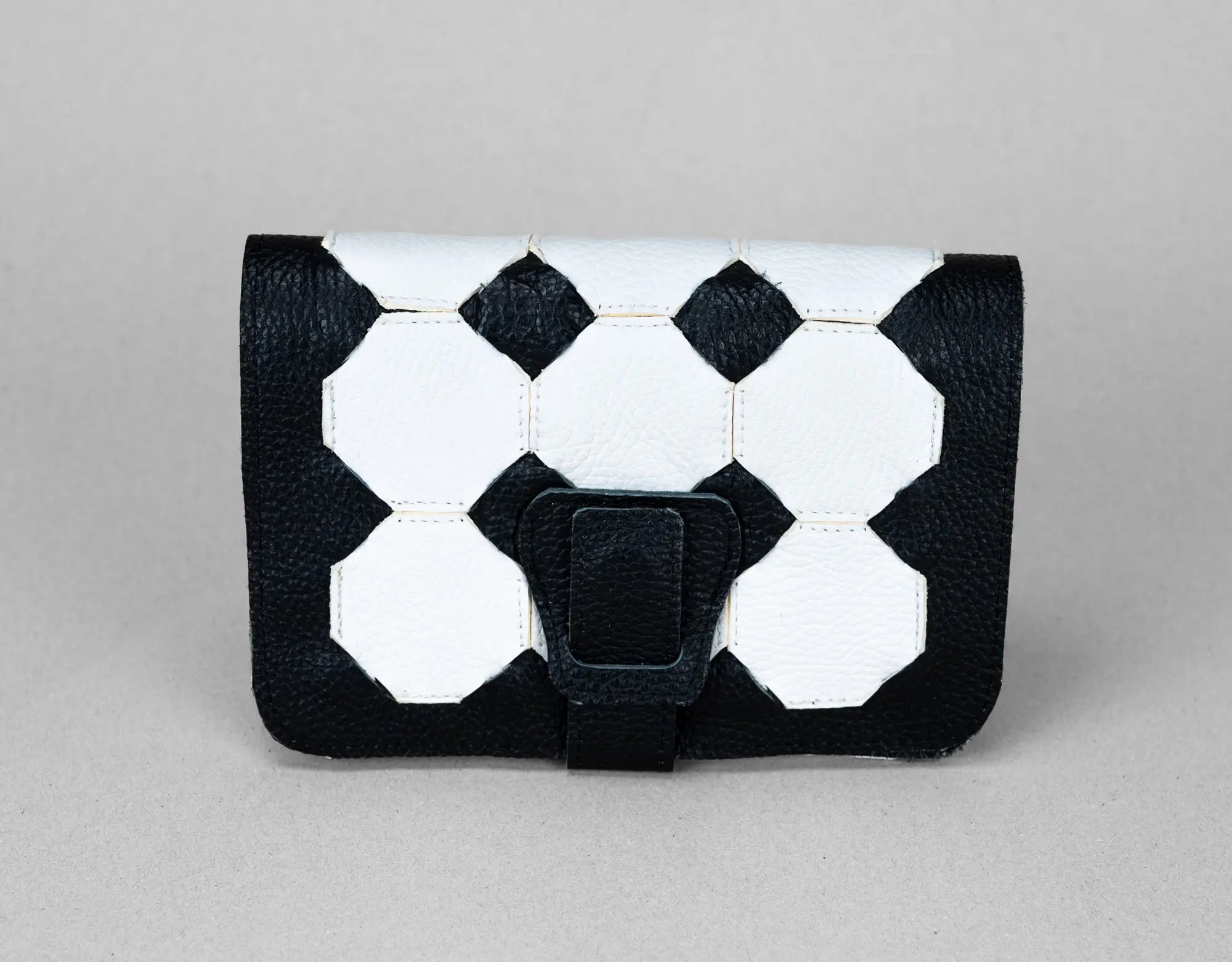 Black and white geometric patterned clutch bag on a gray background