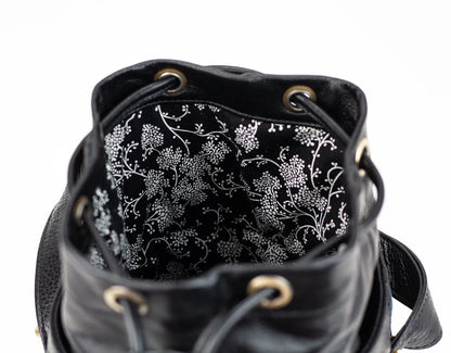 Black leather bag with floral patterned interior on a white background