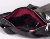 Black handbag with open zipper showing a red interior on a light gray background