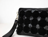 Black textured clutch bag with a strap on a white background