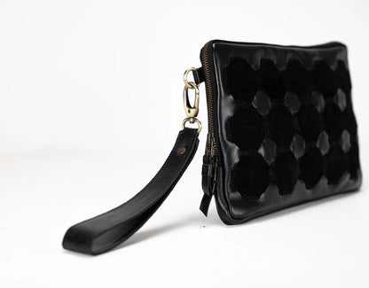 Black quilted clutch bag with a strap on a white background