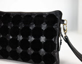 Black quilted handbag with a strap on a light background