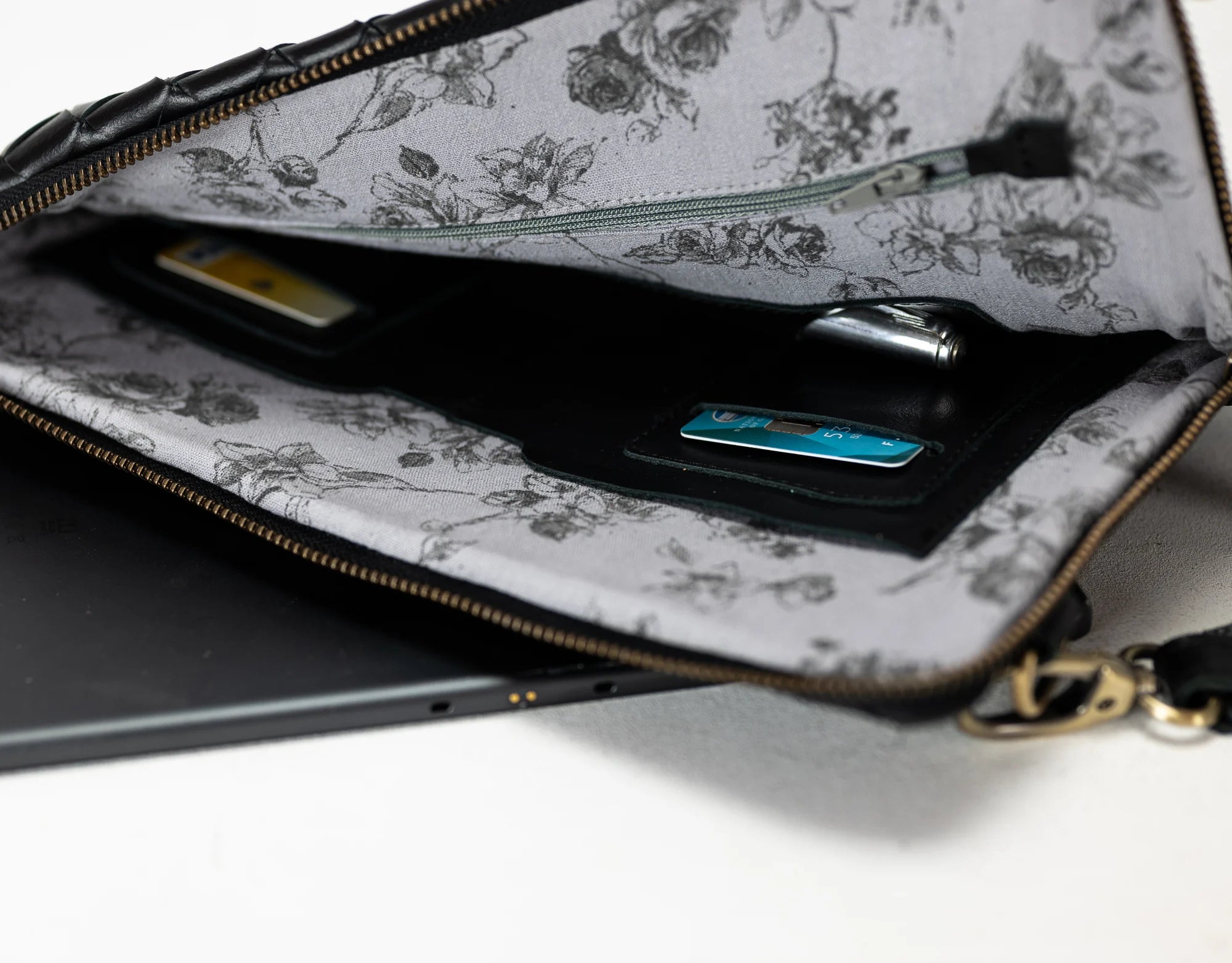 Floral-patterned clutch bag with a phone and wallet inside on a white background