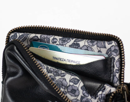 Black leather wallet with floral lining holding a bank card on a white background