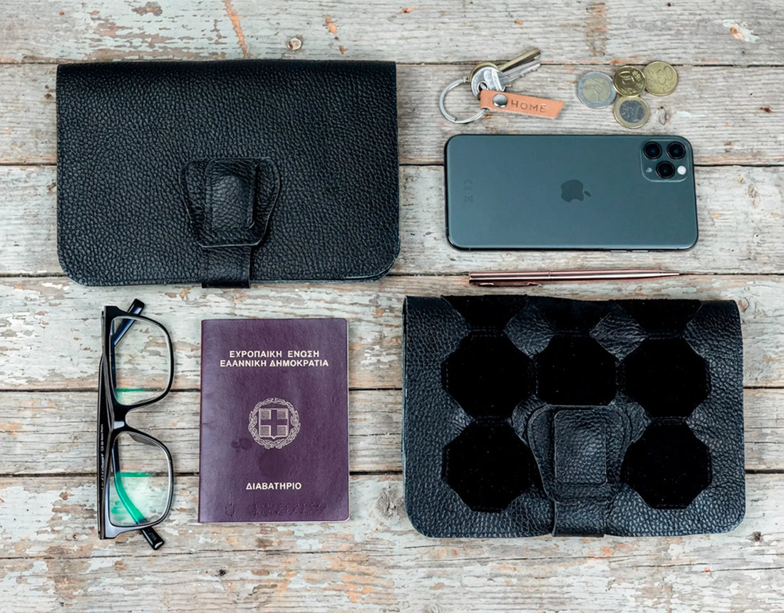 Collection of everyday items including a black leather wallet, phone, glasses, passport, and ice cube tray on a wooden surface.
