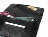Black wallet with phone, cards, and coins on a white background