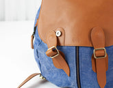 Blue backpack with brown leather straps and accents on a white background
