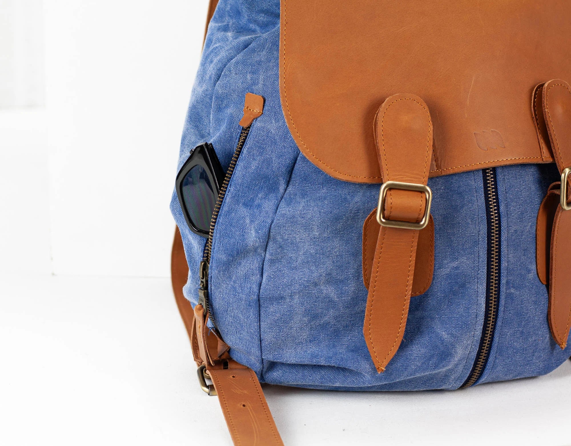 Blue backpack with brown leather straps and accents on a white background