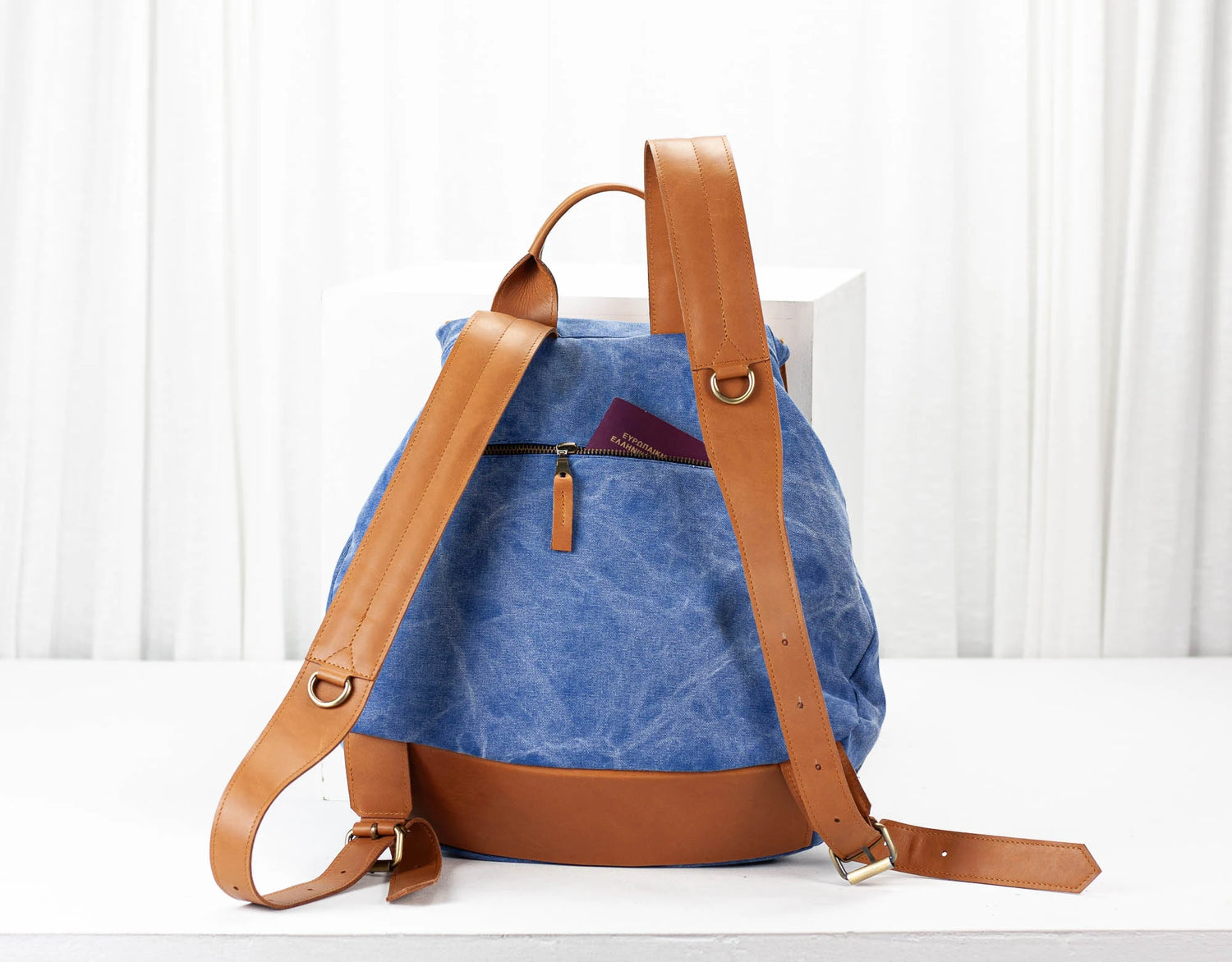 Blue backpack with brown leather straps on a white background