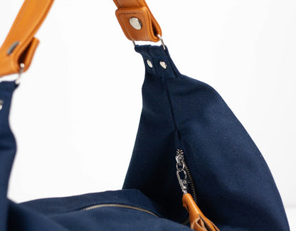 Navy blue bag with brown leather strap on a white background