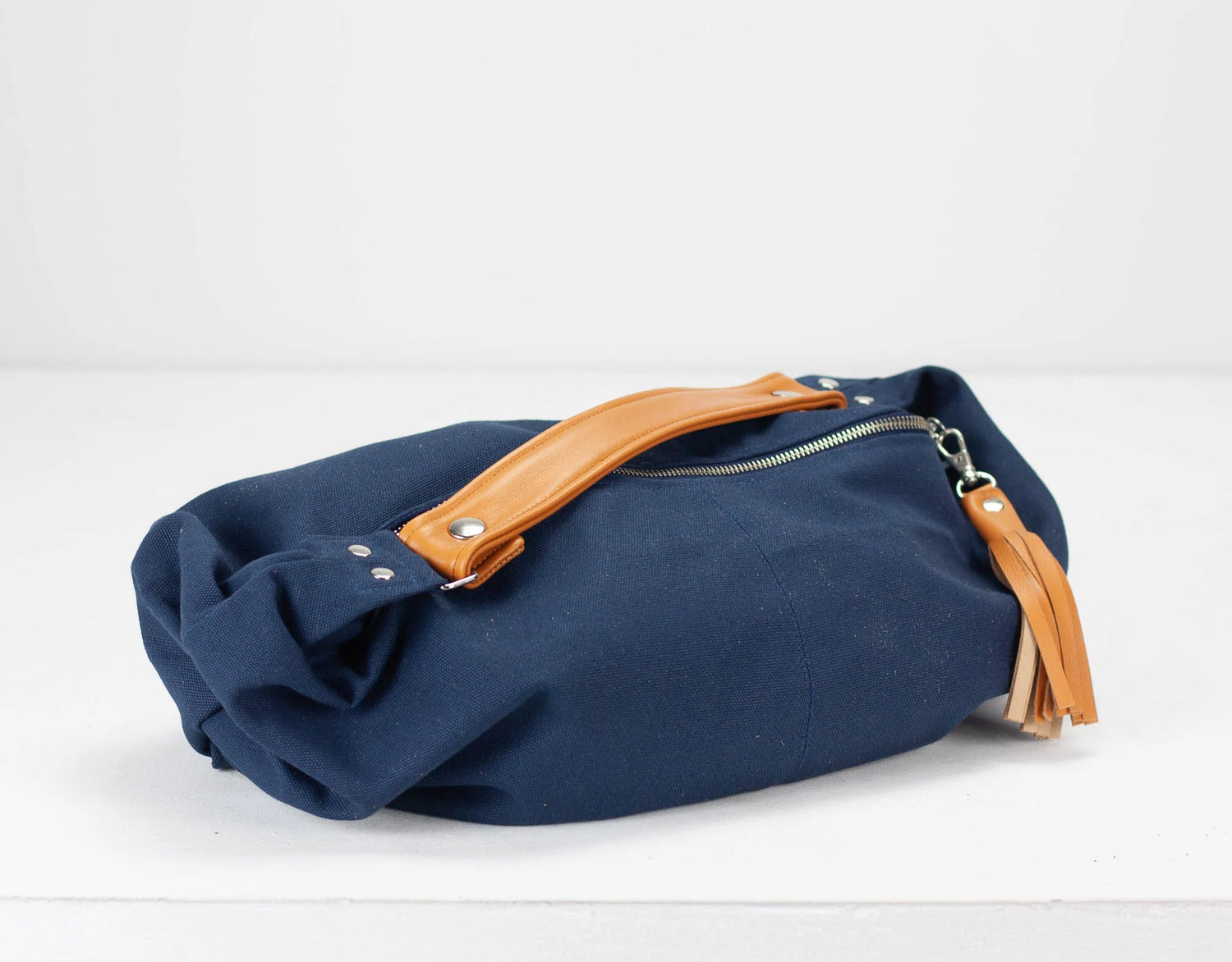 Navy blue bag with brown leather handle on a white background