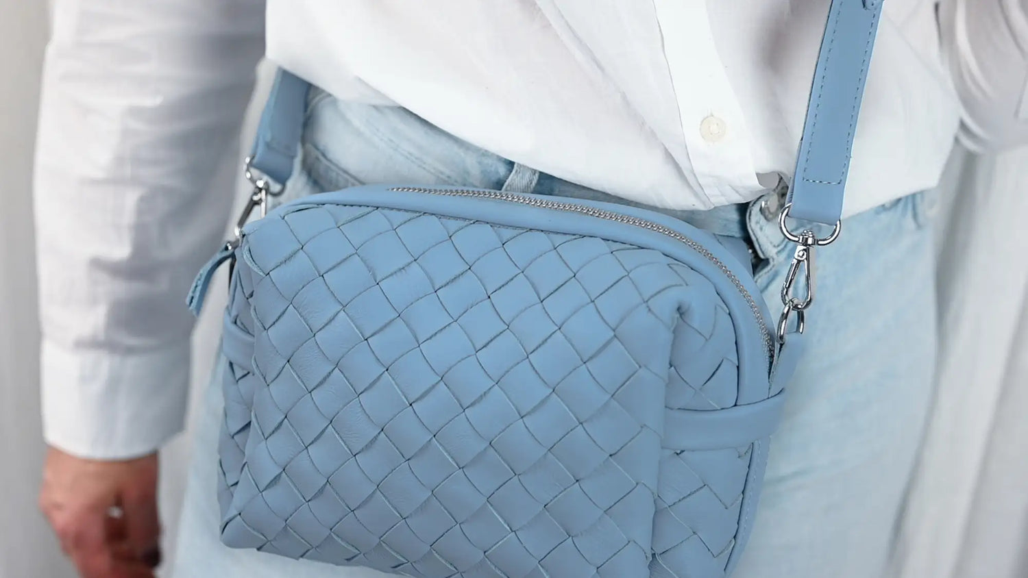 Light blue woven handbag worn over the shoulder against a neutral background