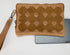 Brown quilted clutch bag with a strap on a white surface next to a tablet.