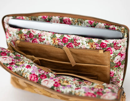 Floral-patterned clutch with a laptop inside on a white background