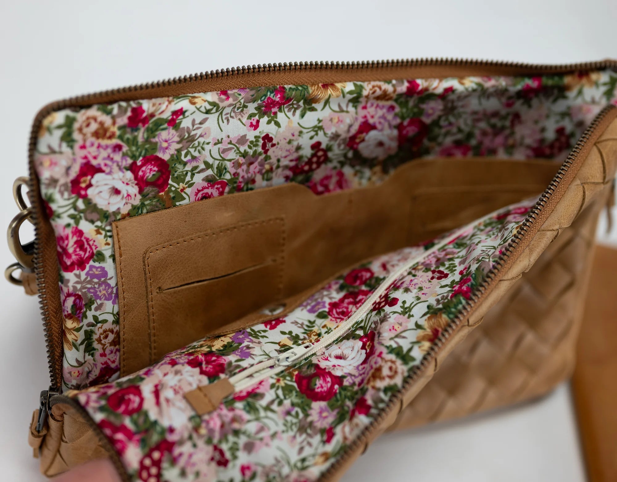 Floral-patterned clutch with brown leather trim on a white background
