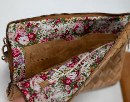 Floral-patterned clutch with brown leather trim on a white background