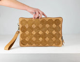 Brown textured clutch bag with a hand holding it against a light gray background