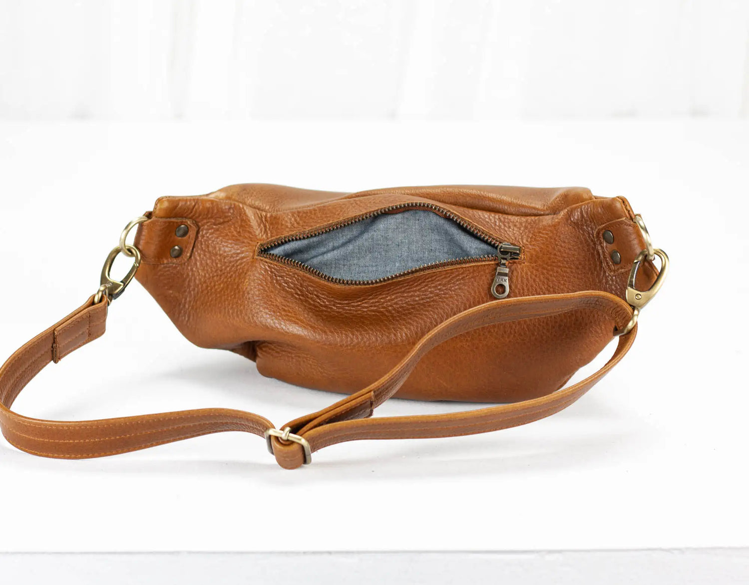 Brown leather handbag with a visible zipper on a white background
