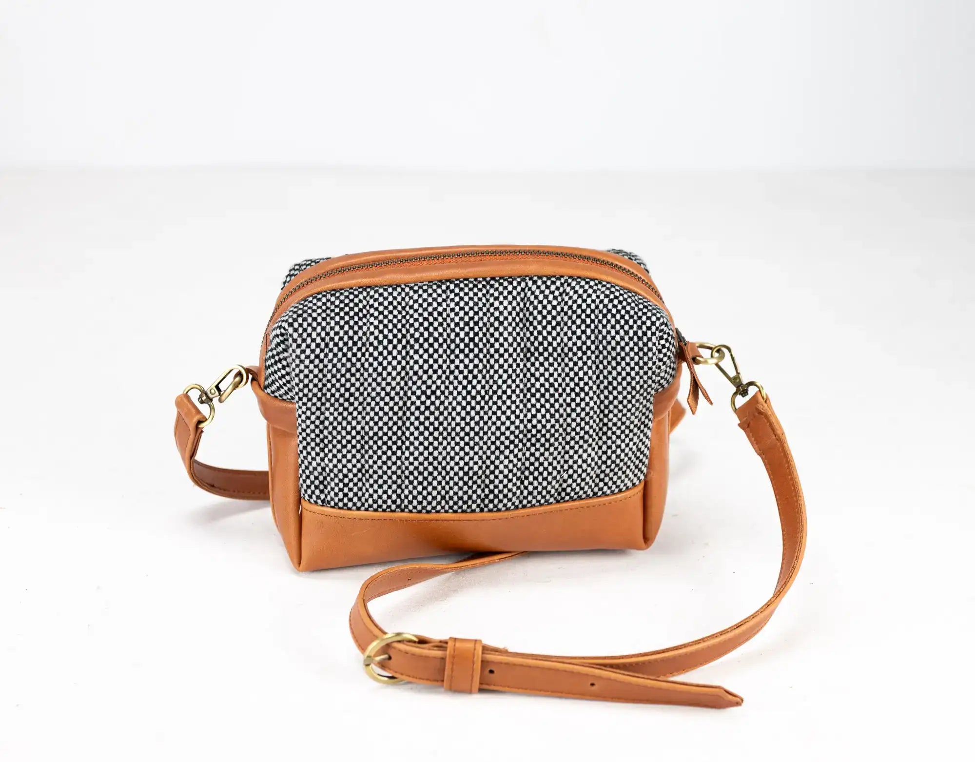 Small crossbody bag with herringbone pattern and brown leather accents on a white background