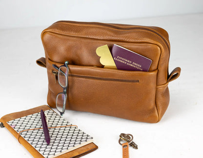 Brown leather bag with eyeglasses, wallet, and key on a white background