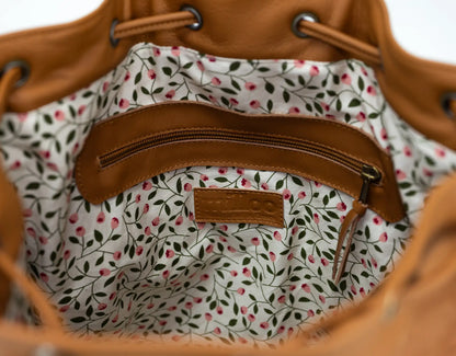 Close-up of a brown leather bag with a floral interior lining.