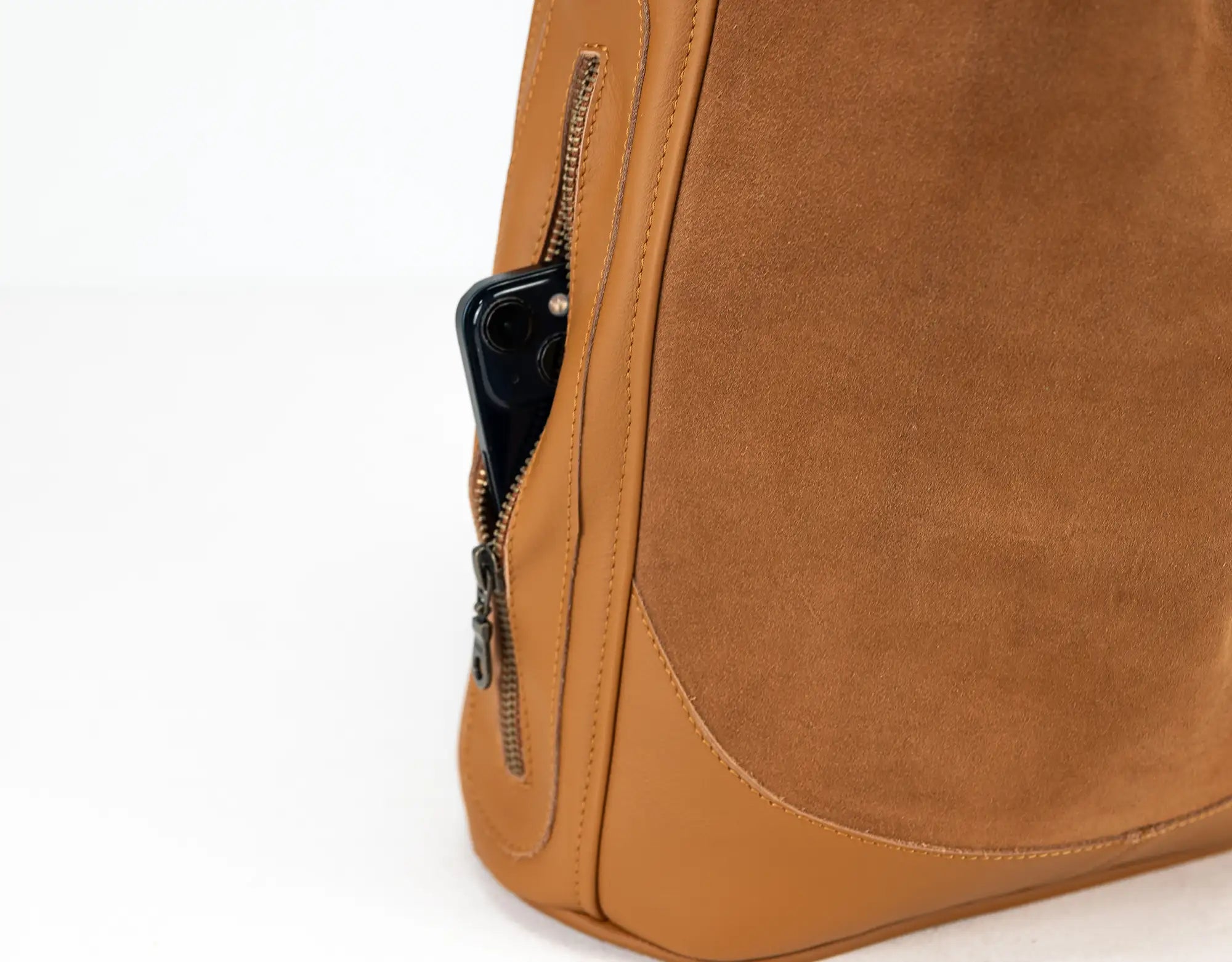 Close-up of a brown leather bag with a zipper pocket on a white background