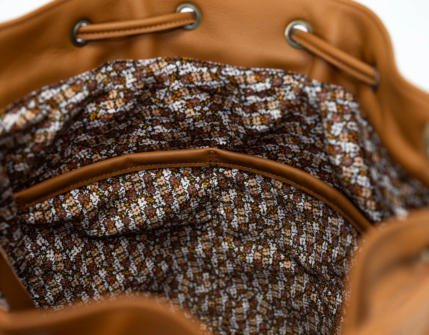 Close-up of a brown leather bag with a patterned interior lining.