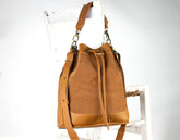 Brown leather drawstring bag on a white chair with a white background