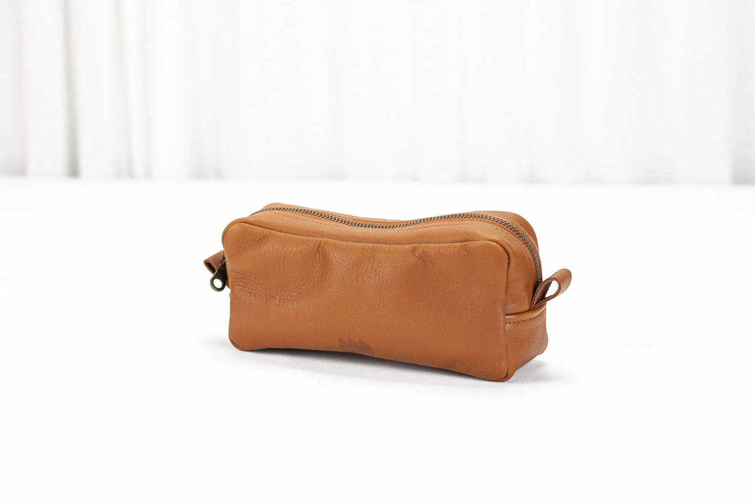 Brown leather toiletry bag on a white background