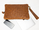 Brown woven clutch bag with a phone and laptop on a white background